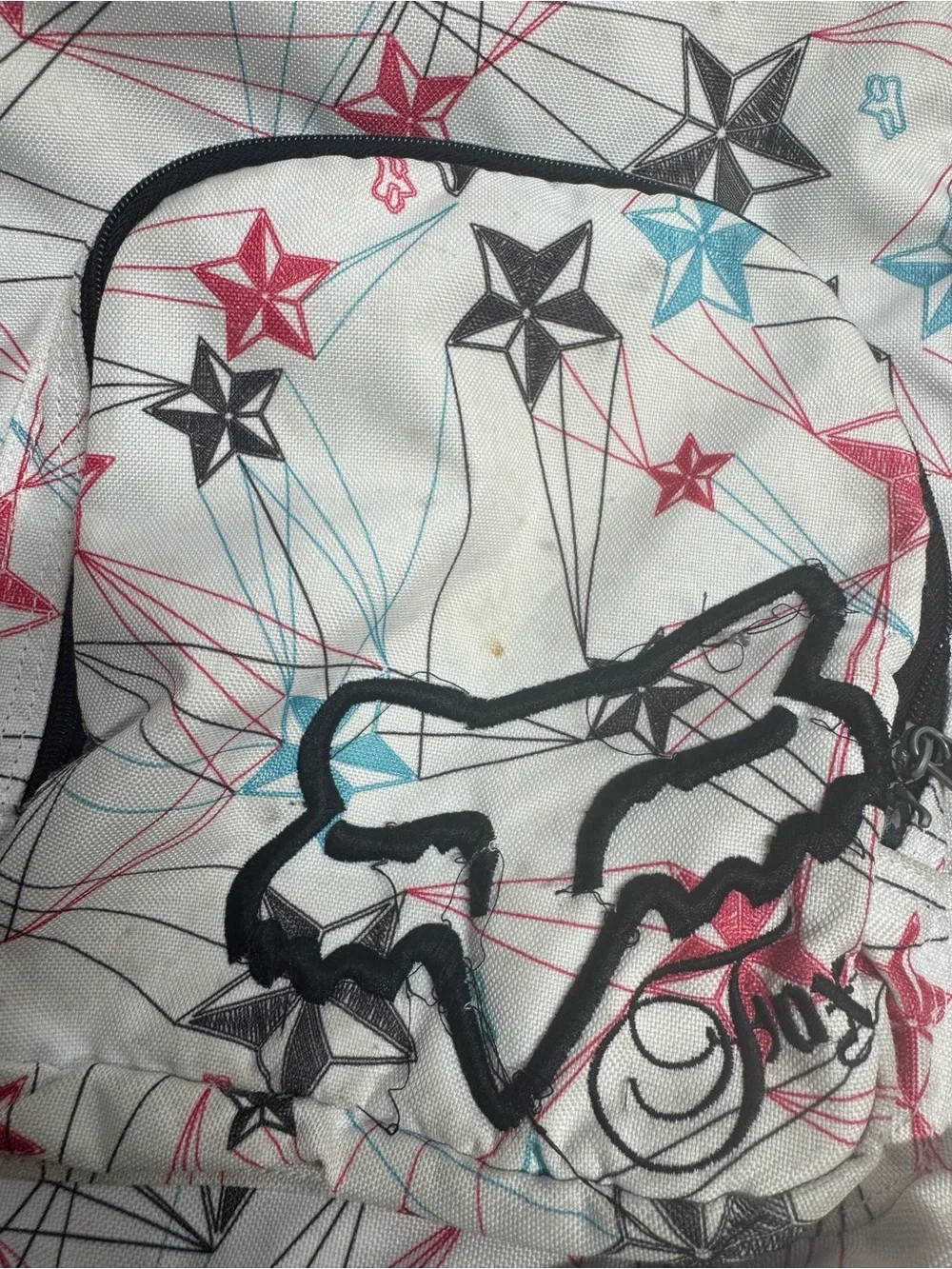 Fox Racing white polyester backpack with red, blue, and black stars and lines